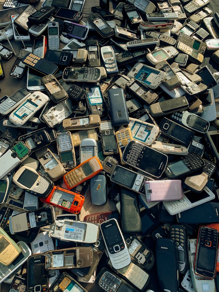 A collection of old and obsolete mobile phones stacked for recycling purposes.